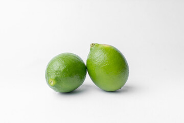 Two whole, fresh green limes isolated on a clean white studio background. Healthy citrus fruit, rich in vitamin C. Perfect minimalist image with ample copy space.