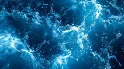 Deep azure ocean water surface displays agitated foam patterns from above