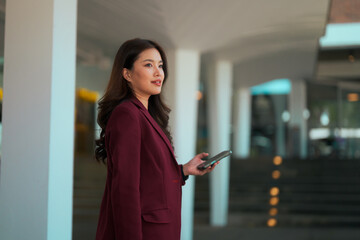 Asian businesswoman using smartphone feeling thoughtful in city