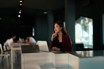 Asian businesswoman thinking and looking away in modern office