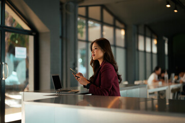 Asian businesswoman using smartphone at modern coworking office