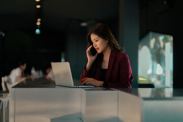 Asian businesswoman multitasking, talking on phone, using laptop