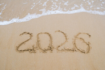 The inscription 2026 on the sand by the sea. Happy New Year.