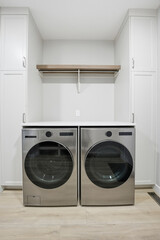Two silver washing machines are in a white room