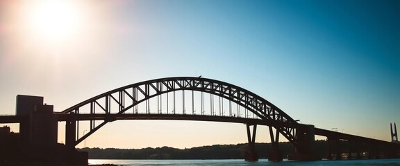 Sleek, dark bridge silhouette against a bright sky,  dawn,  outdoor