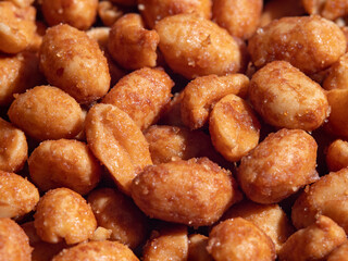 close-up view of pile of crunchy seasoned peanuts, showcasing their golden brown color and crispy texture. These nuts often enjoyed as tasty snack or appetizer at parties