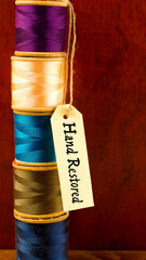Vertical stack of colorful threads with hand restored label on wooden background