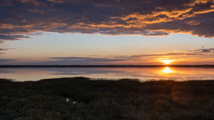 wonderful sunset by the lake, autumn landscape, sun rays reflecting on the calm surface of the lake