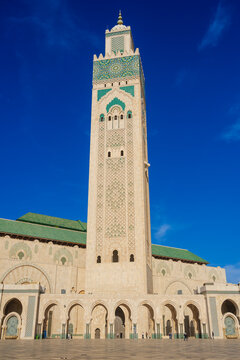 Majestic mosque with intricate archways and towering minaret under a bright blue sky. Casablanca, Morocco