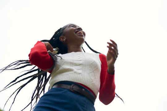 Smiling girl with braided hair and colorful clothing looks joyful against a bright sky. Bruges, Belgium