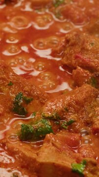 Cooking chicken Indian curry, tikka masala, chicken, lamb, mutton Rogan Josh grill boiling on pan, sauce. Dark background. Close up.
