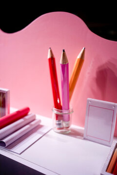 Pink and orange pencils in a glass holder against a pink backdrop with papers. Blankenberge, West Flanders, Belgium