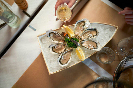 Elegant oyster platter on ice with lemon, parsley, and a glass of white wine. Blankenberge, West Flanders, Belgium