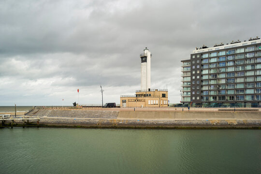 Coastal cityscape with a lighthouse, modern buildings, and cloudy skies. Blankenberge, West Flanders, Belgium