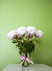 Soft white peonies with gentle petals on a green background. A serene and romantic still life.