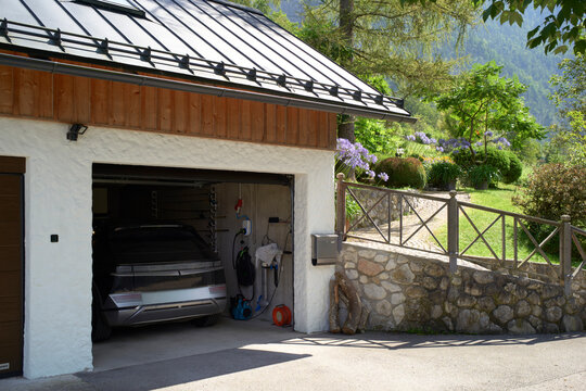 Open garage with electric car in a scenic mountain village setting Salzkammergut, Dachstein Mountains, Austria
