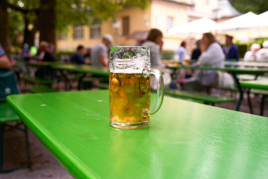 Glass of beer on a green table in an outdoor beer garden setting. Munich, Germany
