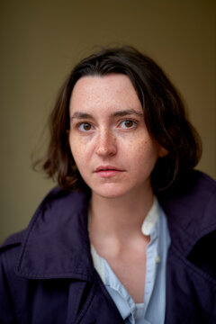 Young Woman with short hair wearing a dark coat, gazing directly at the camera. Brussels, Belgium