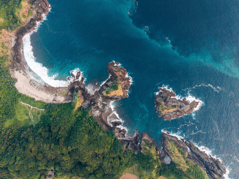 Aerial view of a rugged coastline with lush greenery and deep blue ocean waters. Lombok, Semeti, Indonesia