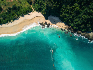 Aerial view of a secluded beach with turquoise waters and lush green forest. Lombok, Resto Nine, Indonesia