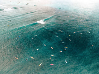 Aerial view of surfers on colorful boards scattered across ocean waves. Lombok, Tanjung Ann, Indonesia