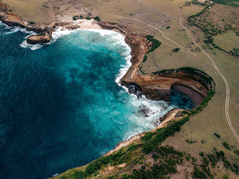 Aerial view of a stunning coastal landscape with cliffs, blue ocean waves, and green terrain. Lombok, Sekaroh, Indonesia