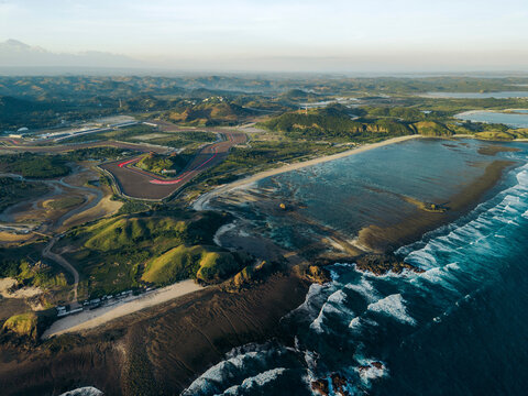 Aerial view of a scenic coastal landscape with rolling hills and a curving road near the ocean. Pertamina Mandalika International Circuit, Kuta, Pujut, Central Lombok Regency, West Nusa, Indonesia