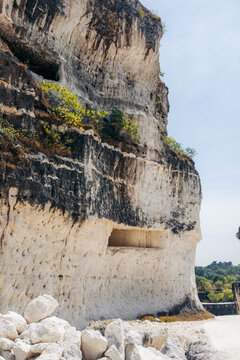 Rocky cliff with natural caves under a clear blue sky Madura, East Java, Indonesia
