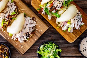 Bao Buns with pulled chicken and vegetables on wooden table. Top view