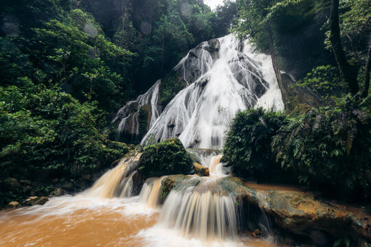 Lush green waterfall cascading over rocks surrounded by tropical forest. Ambon, Maluku, Indonesia