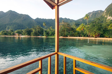 A serene mountain view from a waterside balcony with clear turquoise water and lush greenery. Saleman Village, Seram Island, Maluku, Indonesia