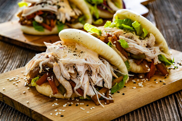 Bao Buns with pulled chicken and vegetables on wooden table	