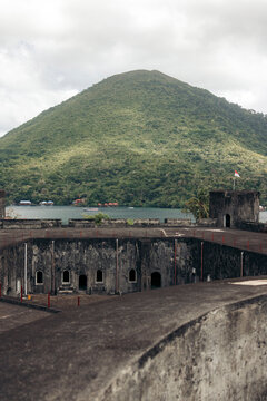 Historic fort with arched windows and a lush green mountain in the background. Banda Neira, Banda, Central Maluku Regency, Indonesia