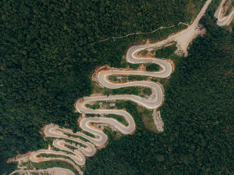 Aerial view of a winding mountain road surrounded by lush green forest.  Khau Coc Cha Mountain Pass, Bao Lac, Cao Bang, Vietnam