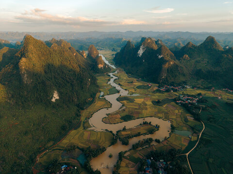 Aerial view of a winding river through lush green valleys and mountainous landscape at sunset. Phong Nam, Tr˘ng Kh&middot;nh District, Cao Bang, Vietnam