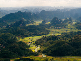 Aerial view of lush green valleys and distant mountain peaks under a cloudy sky. Phong Nam, Tr˘ng Kh·nh District, Cao Bang, Vietnam