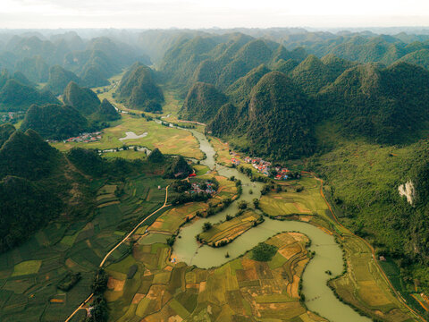 Aerial view of lush green valleys and meandering river amidst scenic mountain landscape. Phong Nam, Tr˘ng Kh&middot;nh District, Cao Bang, Vietnam