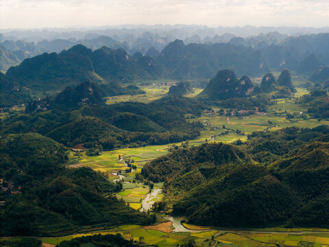 Aerial view of lush green valleys and distant mountain peaks under a cloudy sky. Phong Nam, Tr˘ng Kh·nh District, Cao Bang, Vietnam