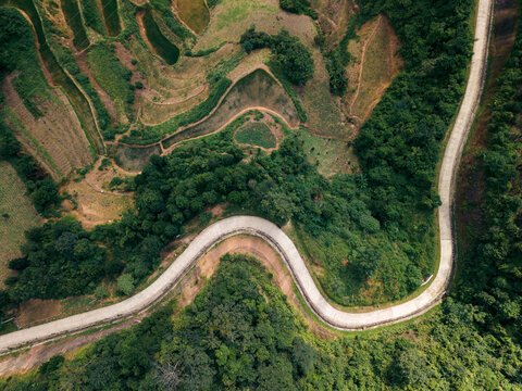 A winding road snakes through lush green hills and terraced fields in a rural landscape. Loc B&Iuml;nh District, Lang Son, Vietnam 