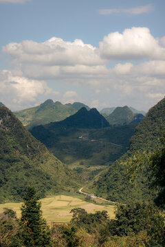 Scenic mountain landscape with lush green valley and winding road under a cloudy sky. Nguy&Iacute;n B&Iuml;nh District, Cao Bang, Vietnam