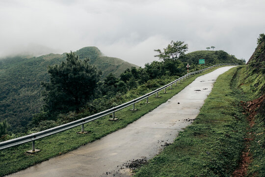 A winding mountain road with misty hills and lush greenery under a cloudy sky. Binh Lieu District, Quang Ninh, Vietnam