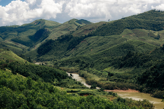 Rolling green hills with a winding river under a sky filled with clouds. Binh Lieu District, Quang Ninh, Vietnam