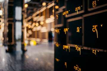 Golden script on dark stone with blurred glowing lights in a modern architectural space. Black Virgin Mountain, Tay Ninh, Vietnam