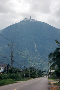 A road leads to a hilltop statue, surrounded by clouds and lush greenery. Black Virgin Mountain, Tay Ninh, Vietnam