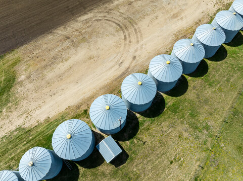 Aerial view of grain silos lined up in a rural agricultural landscape. North of Calgary, Canada