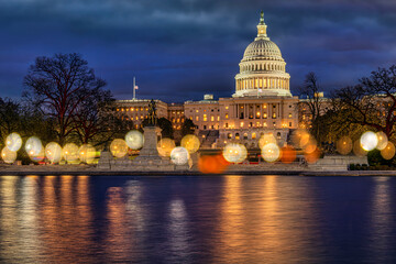 Illuminated US Capitol building at night with reflections on the water. Washington DC, WA, USA