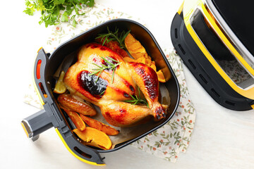 Tasty grilled chicken with rosemary in air fryer on white wooden table, top view