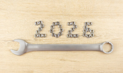 Light wood background with number 2026 by metal nuts with wrench. 2026 year