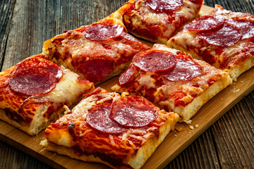 Pepperoni pizza with salami, tomato sauce and mozzarella cheese on wooden table	
