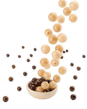 Playful flying mix of tapioca pearl and candy falling into wooden bowl. sweet tasty ingredient for delicious bubble tea or dessert